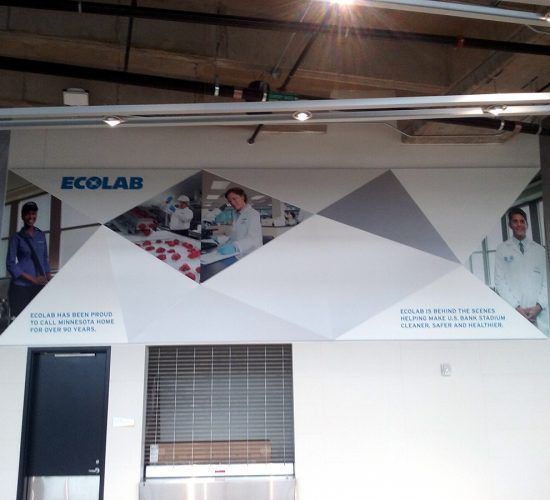 Ecolab wall mural with geometric shapes and lab workers. Text: "Behind the scenes, the future, cleaner together."