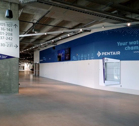 Hallway with signs and blue branding, featuring a water fountain and the Pentair logo.
