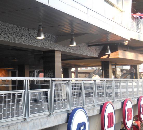 Exterior view of a building with a metal fence and signs with numbers; overhead lights are visible.