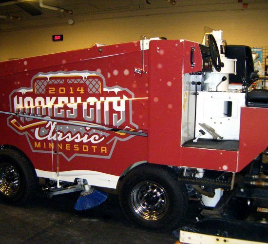 Red Zamboni with "Hockey City Classic Minnesota 2014" logo on side. Snowflakes accent the design.