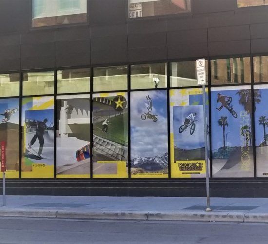 Storefront with large window displays featuring action sports like skateboarding, BMX, and snowboarding.
