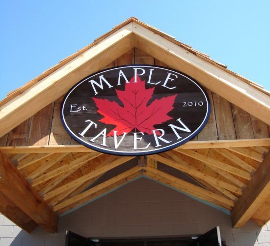 Maple Tavern sign with a red maple leaf, under a wooden awning.