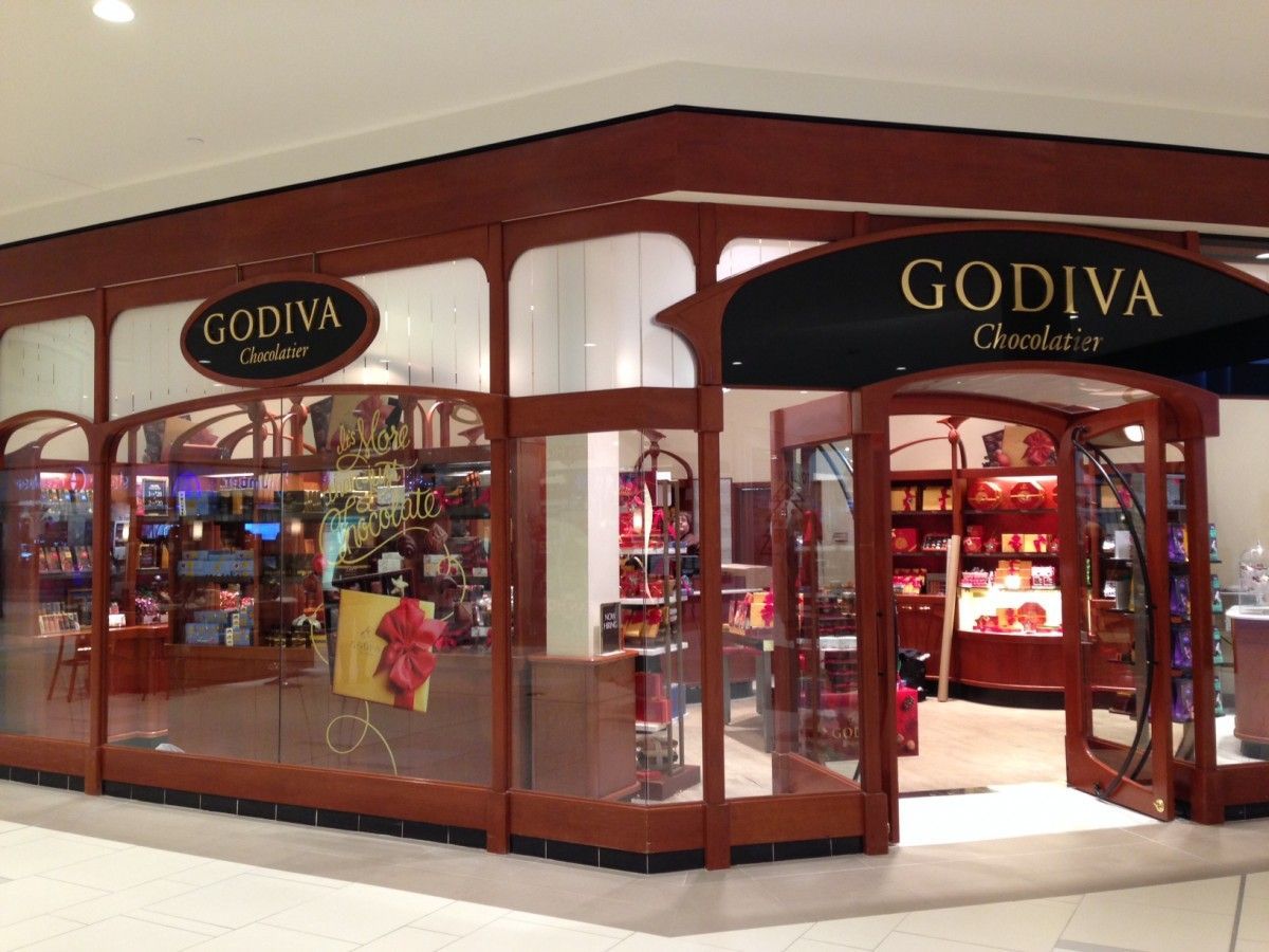 Godiva chocolate store in a mall, featuring glass windows, brown accents, and a sign.