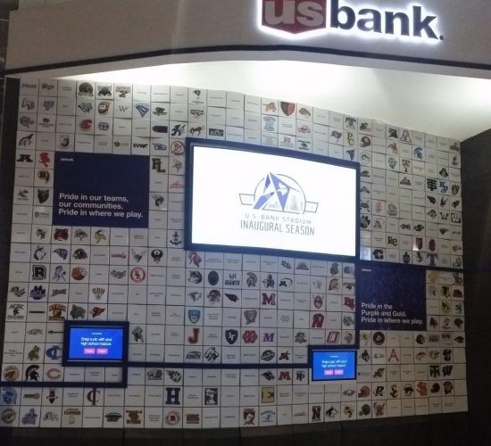 US Bank kiosk with a screen and sports logos on the wall.