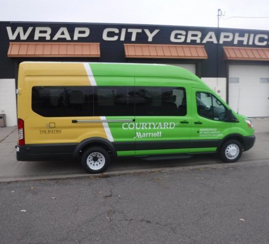 Yellow and green Courtyard Marriott van parked in front of a building with Wrap City Graphics signage.