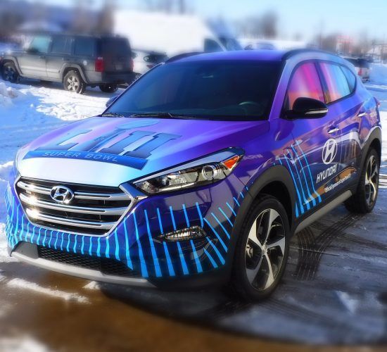 Blue and purple Hyundai Tucson with graphics on a snowy day.