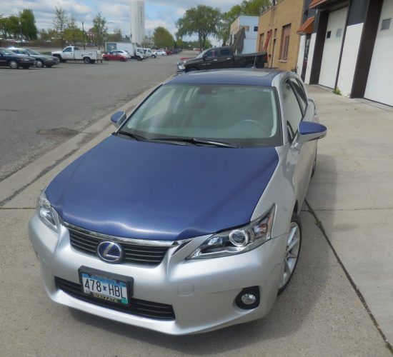 Silver Lexus car with a blue hood parked on a street.