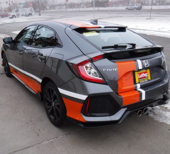 Gray Honda Civic hatchback with orange and white racing stripes, parked on a snowy street.