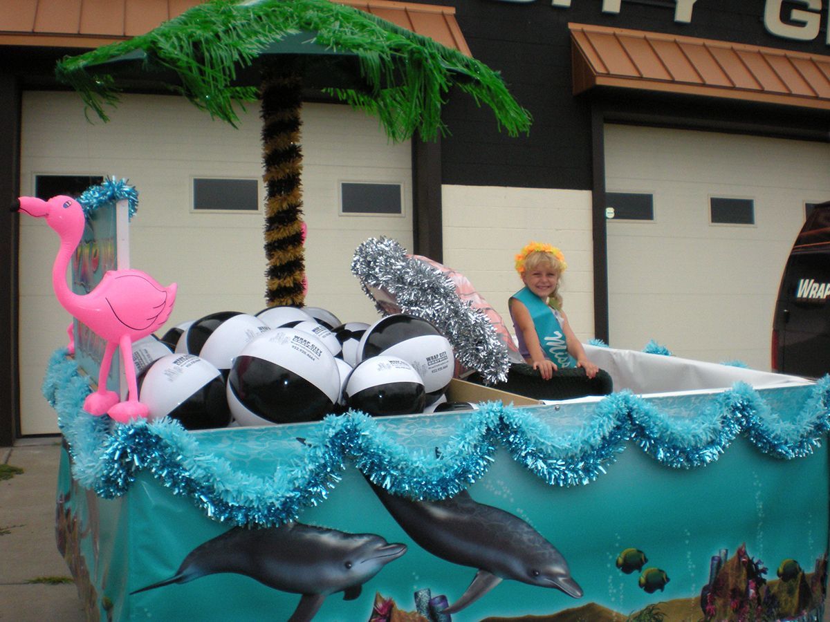 Float with child, beach balls, dolphin backdrop, pink flamingo, and palm tree.