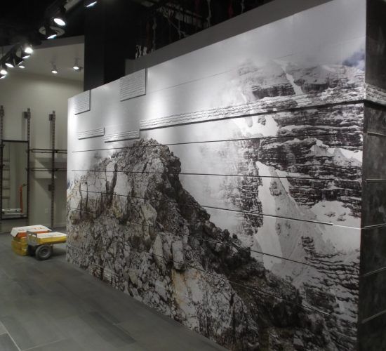 A retail display featuring a mountain scene. The image is on a horizontal panel wall. A small vehicle is nearby.