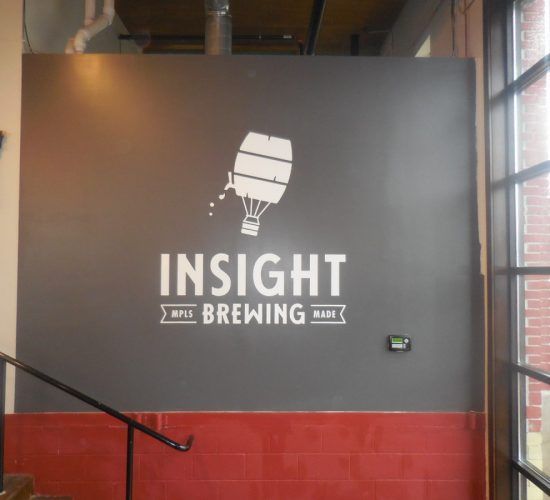 Logo for Insight Brewing on a grey wall: a hot air balloon/barrel graphic with 