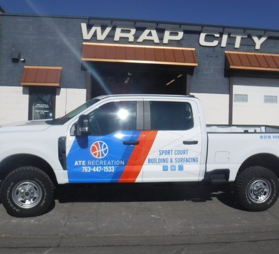White truck with colorful wrap parked in front of 