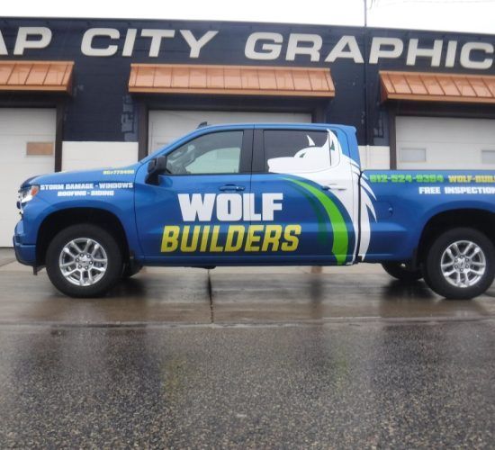 Blue Wolf Builders truck with graphic wrap in front of a building.