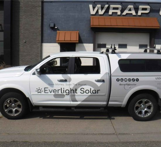 White truck with Everlight Solar branding parked outside a building with 