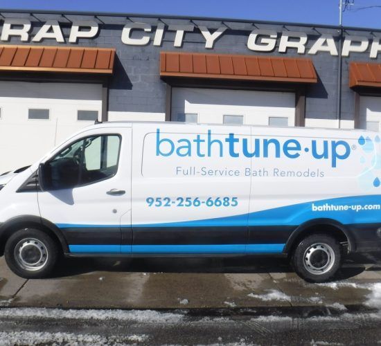 White Bath Tune-Up van with blue accents parked in front of a building.