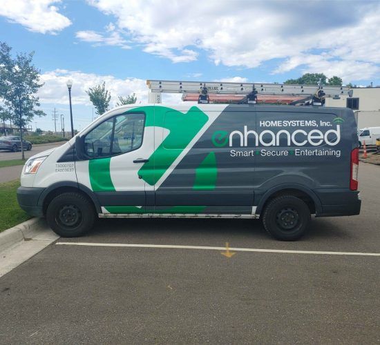 Green and gray Enhanced Home Systems van parked in a parking lot.