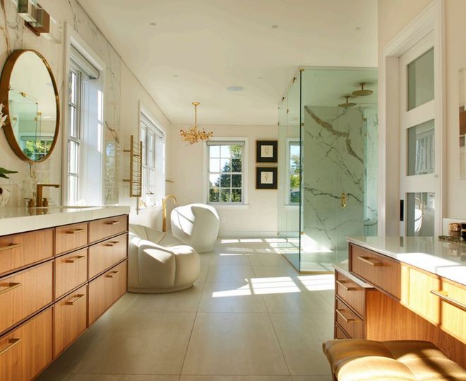 Luxurious bathroom with wood vanity, marble shower, gold accents, and a freestanding tub.