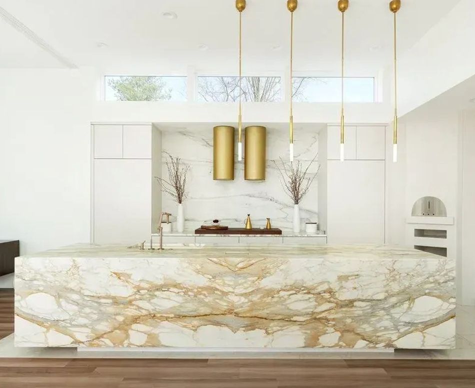 Luxurious kitchen with marble countertops, gold accents, and pendant lights.