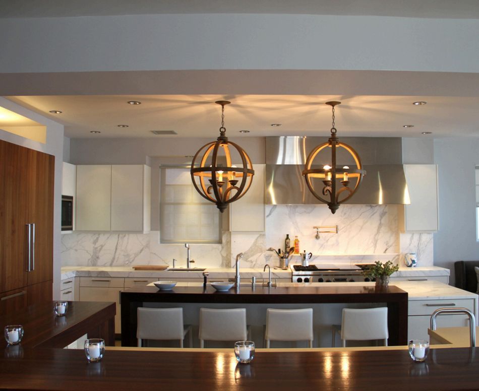 Modern kitchen with white cabinets, marble backsplash, dark wood island, globe pendant lights.
