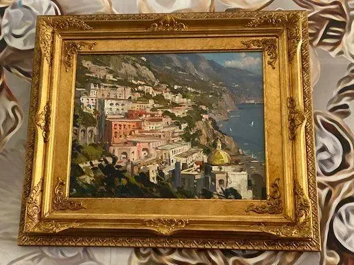 Painting of Positano, Italy, in ornate gold frame; coastal town with colorful buildings, sea, and mountains.