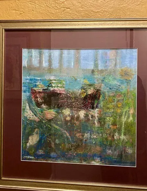 Painting of a boat on a body of water, framed in gold with a red mat, and surrounded by foliage.