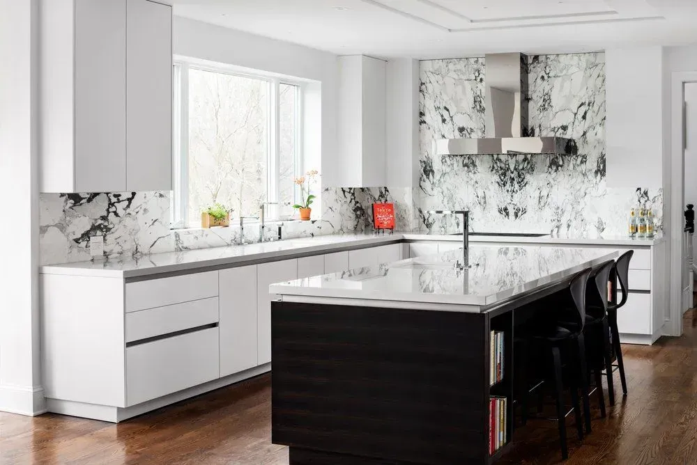 Modern white kitchen with marble accents and a dark island with seating.