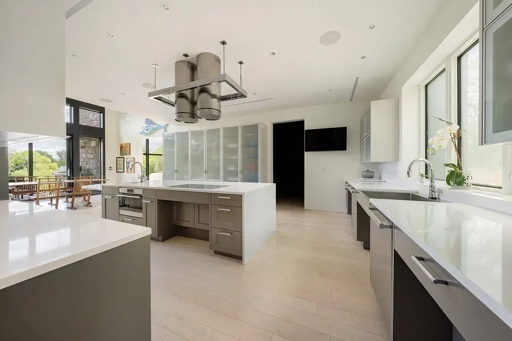 Modern kitchen with gray cabinets, white countertops, and stainless steel appliances.