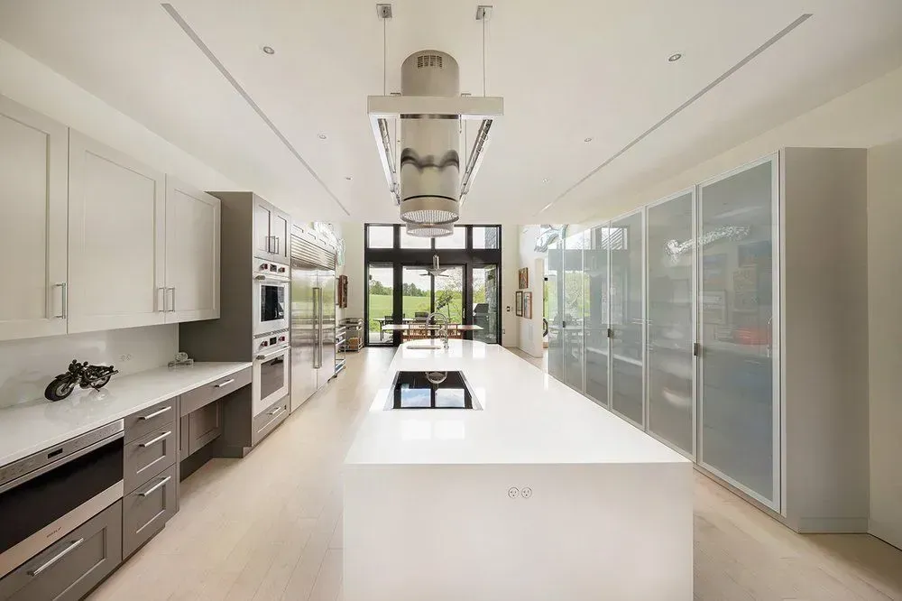 Modern kitchen with large island, stainless steel appliances, and white cabinets.