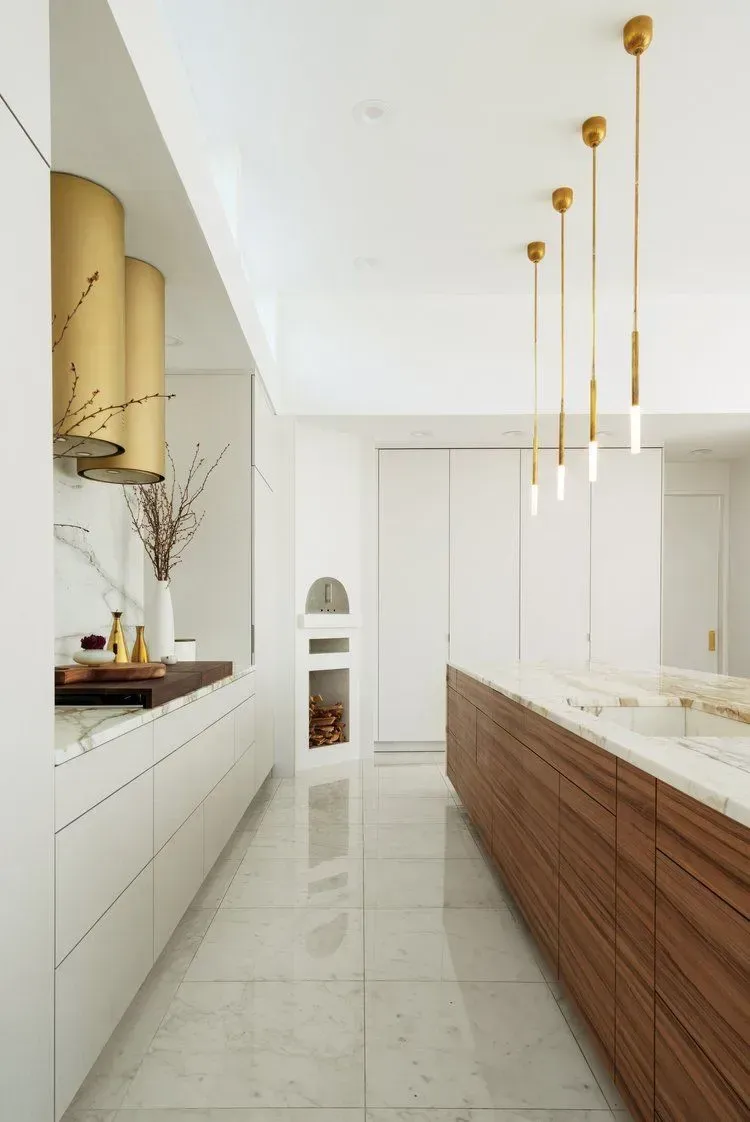 Modern kitchen with white cabinets, wood island, and gold pendant lights.