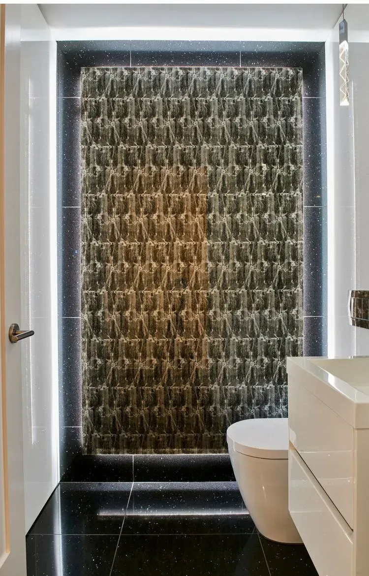 Modern bathroom with waterfall feature, black tile floor, white toilet, and sink.