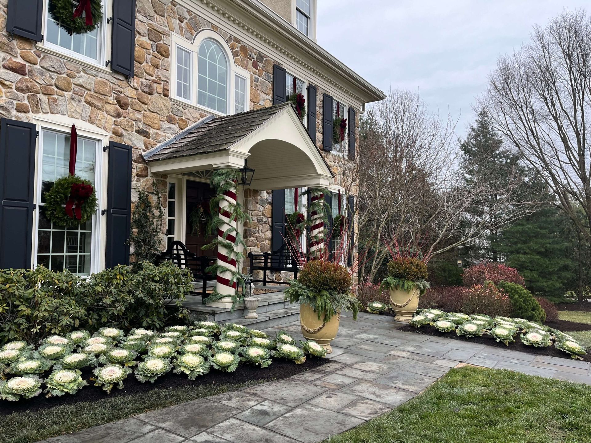 A large stone house with a porch decorated for christmas.