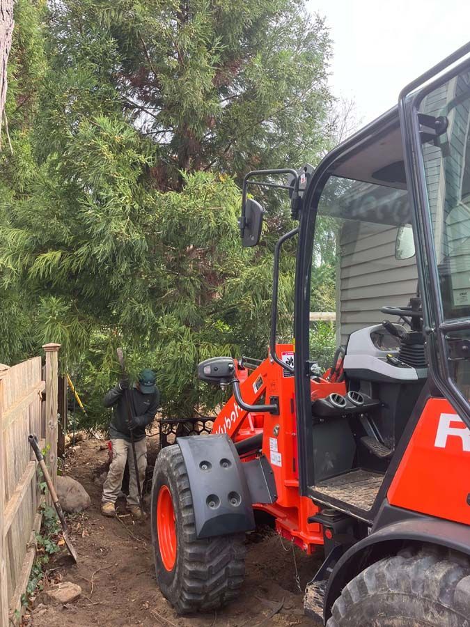 A man is standing next to a red and black tractor.