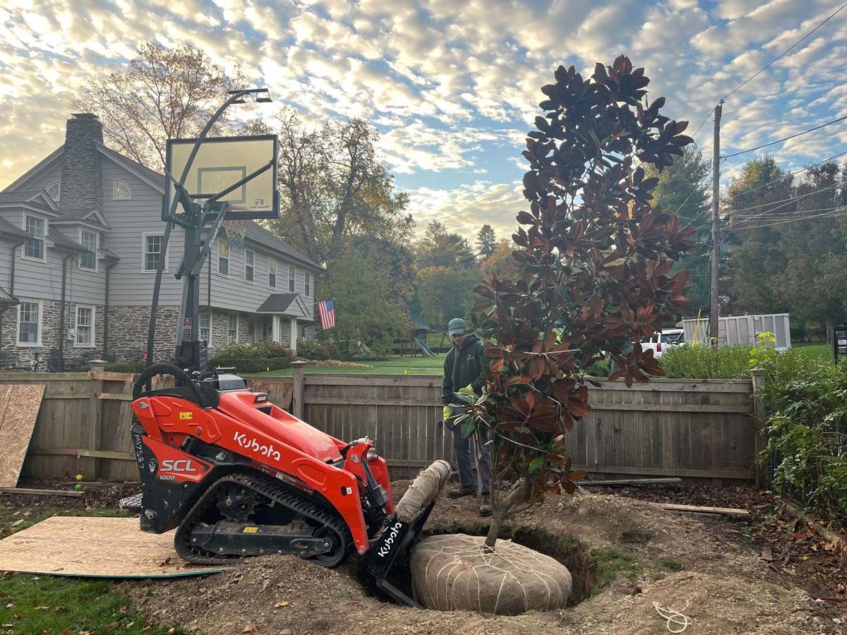 A tractor is digging a hole in the ground next to a basketball hoop.