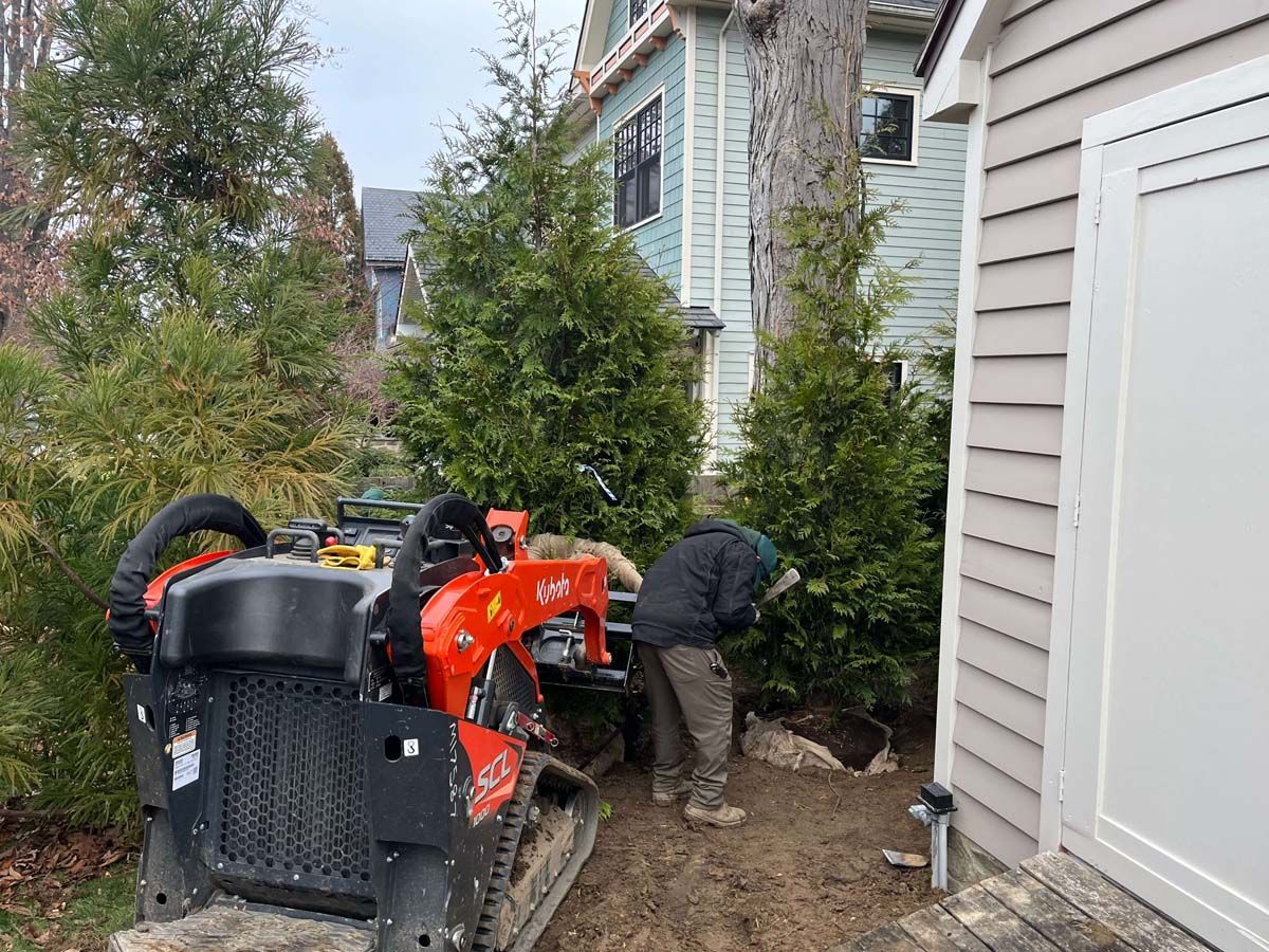 A man is standing next to a tractor in front of a house.