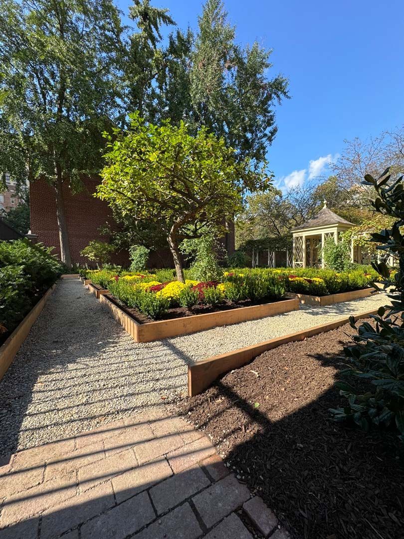 A brick walkway leading to a gazebo in a garden.