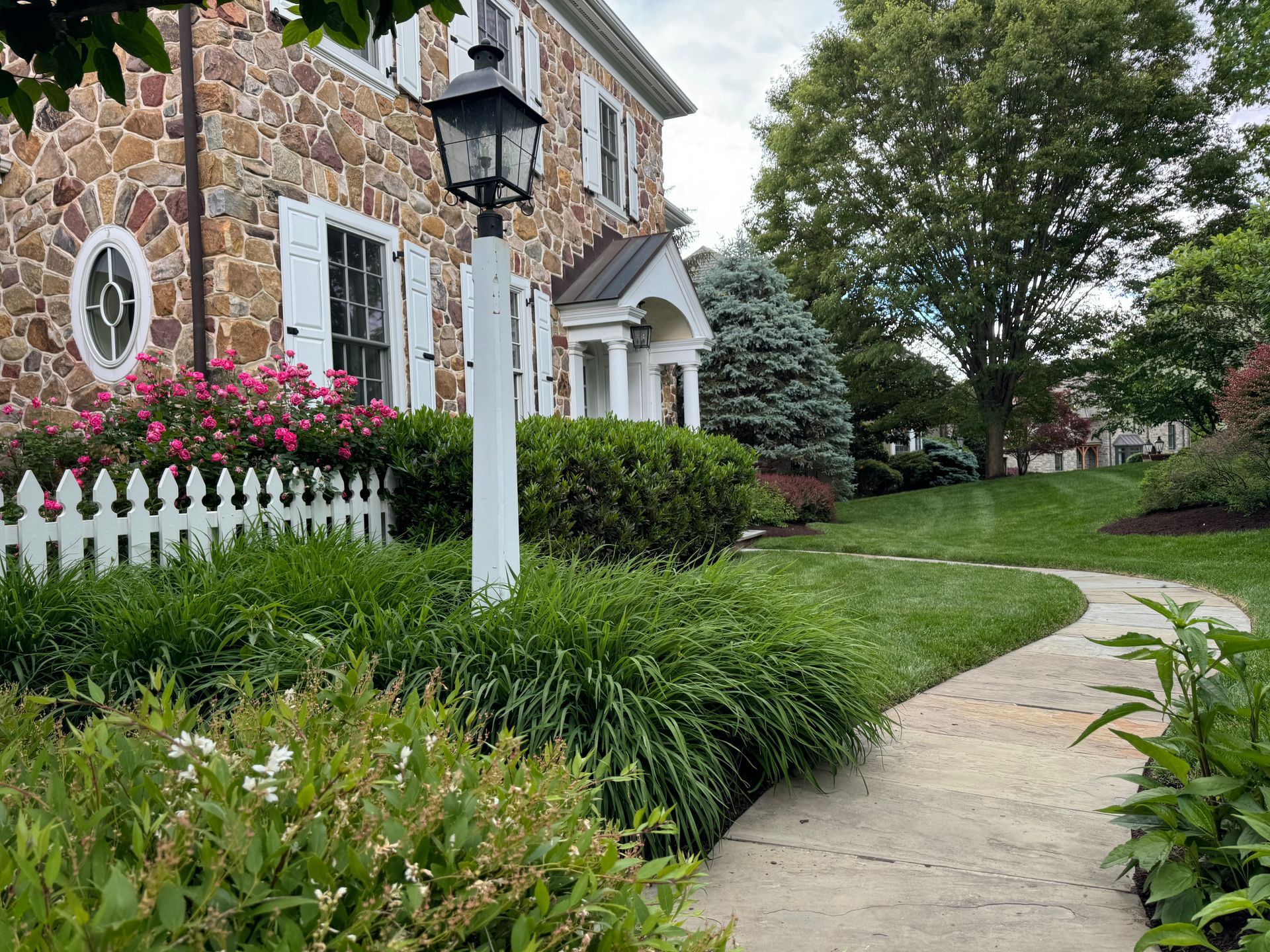 A stone house with a white picket fence and a walkway leading to it.