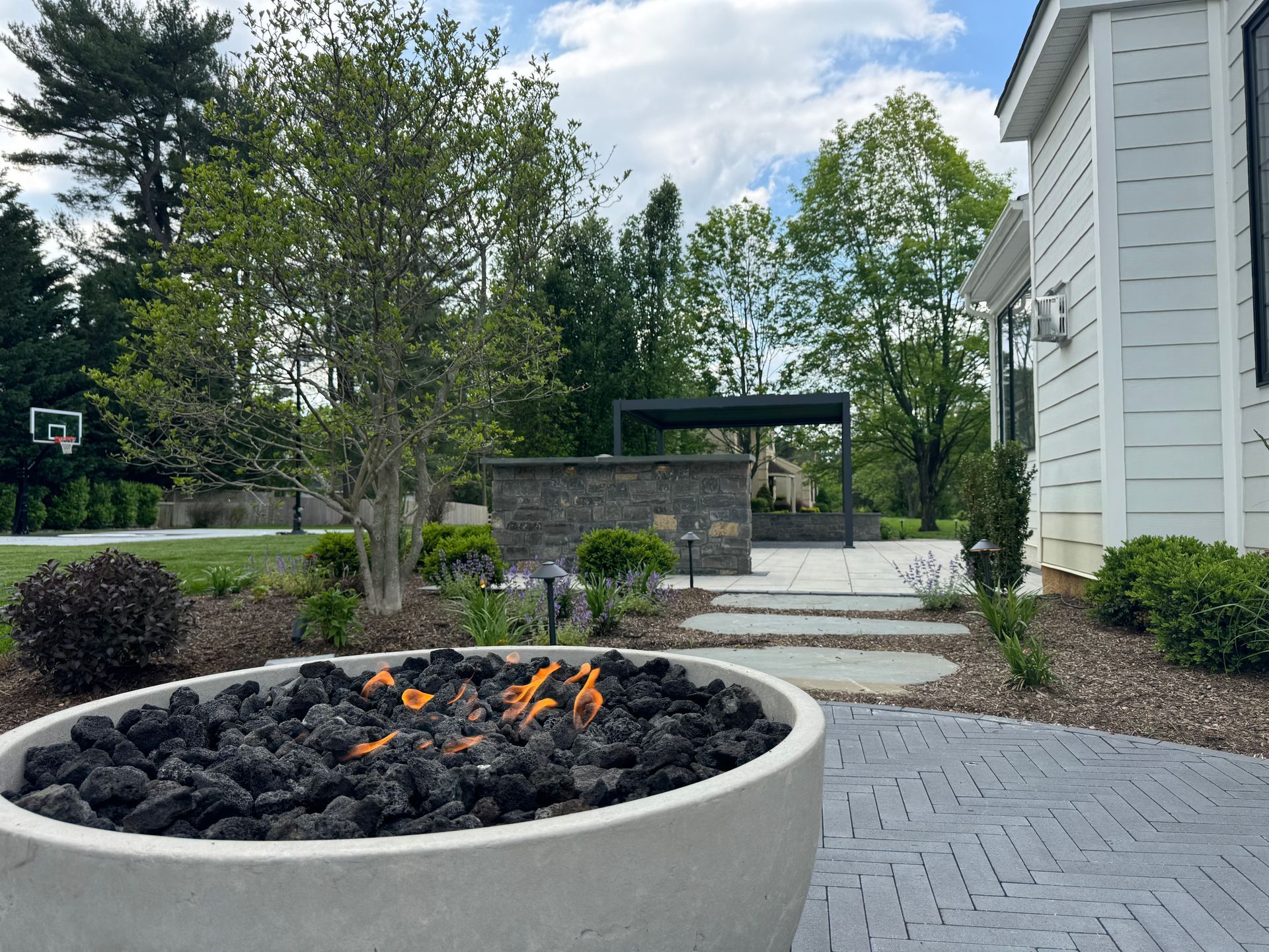A fire pit is sitting on a patio in front of a house.