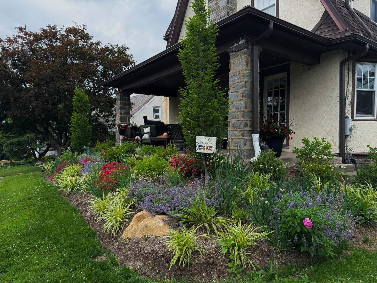 A house with a lush green lawn and flowers in front of it