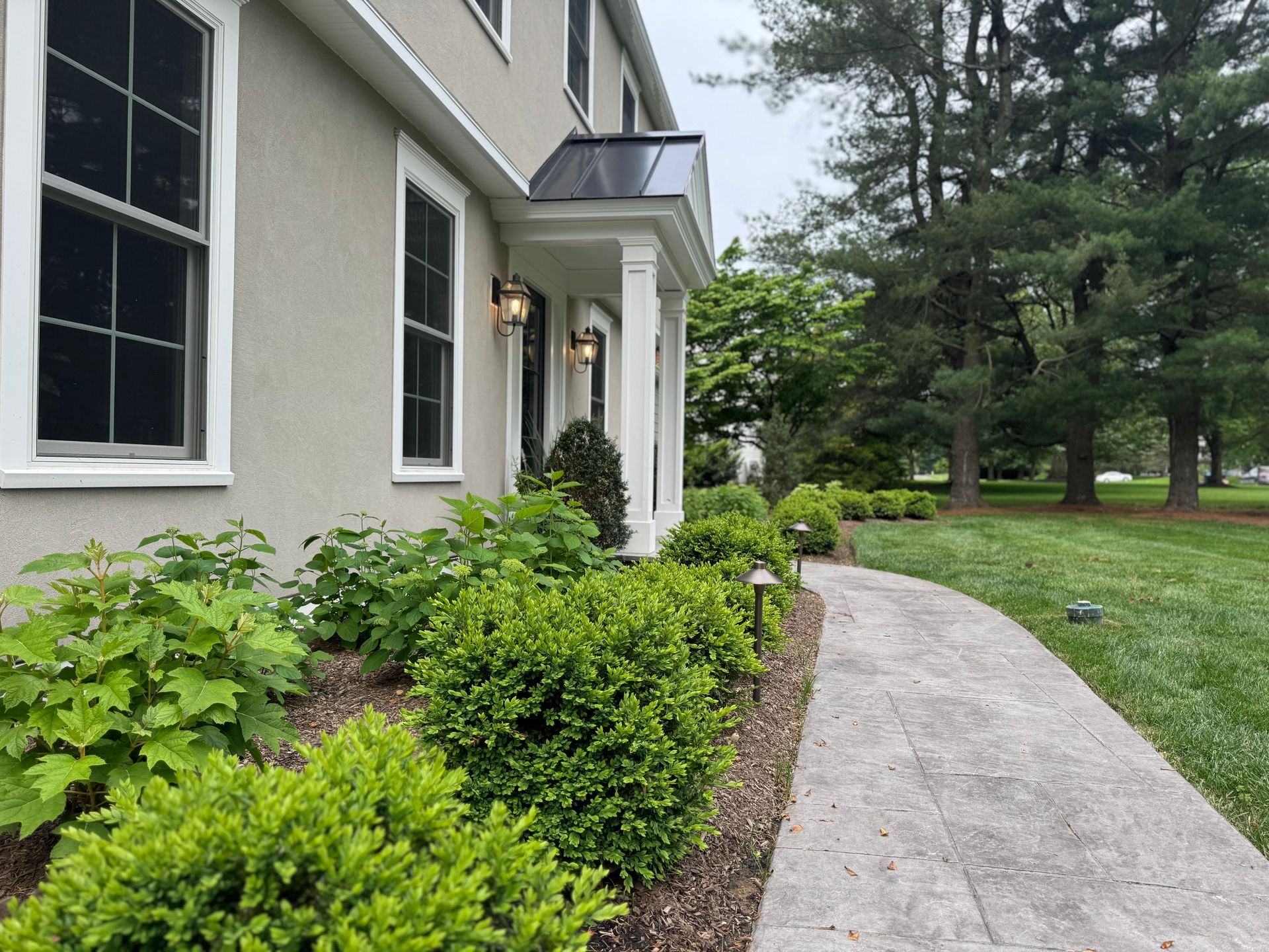 A concrete walkway leading to the front of a house.