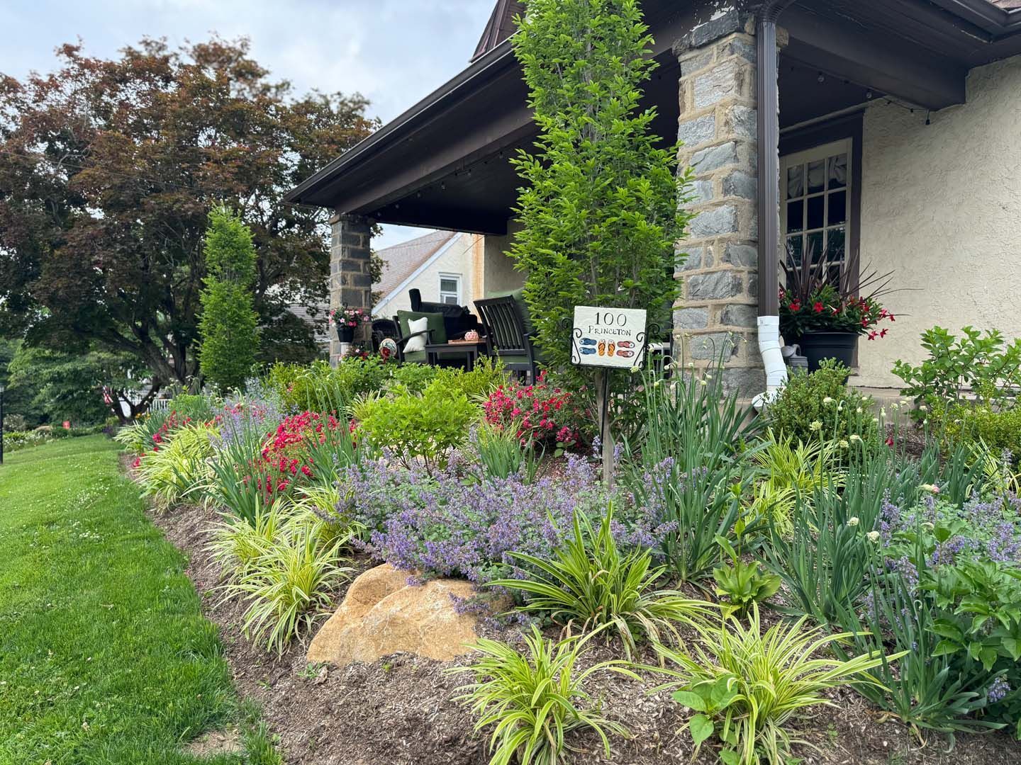A house with a porch and a garden in front of it.