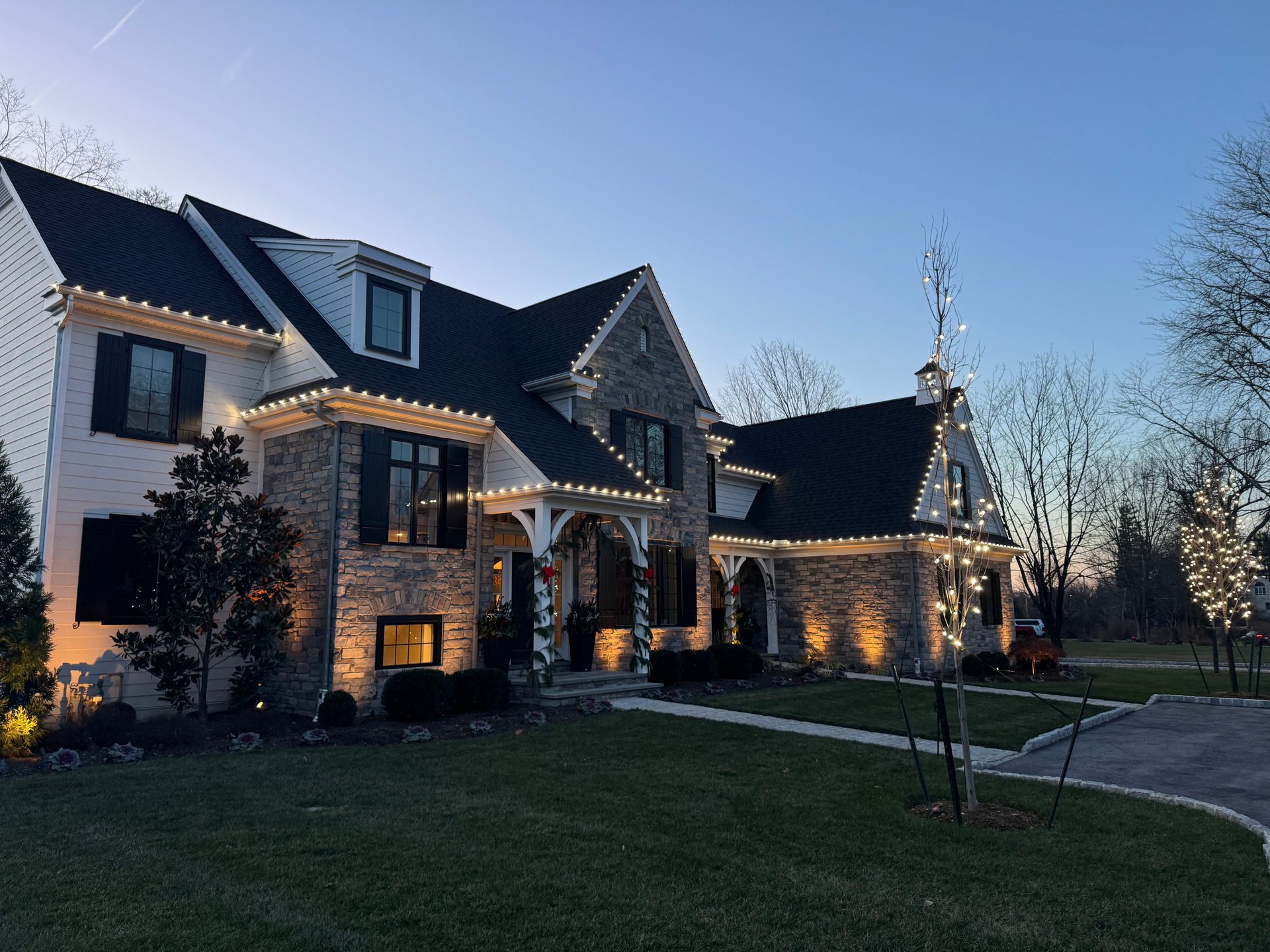A large house with christmas lights on it is lit up at night.