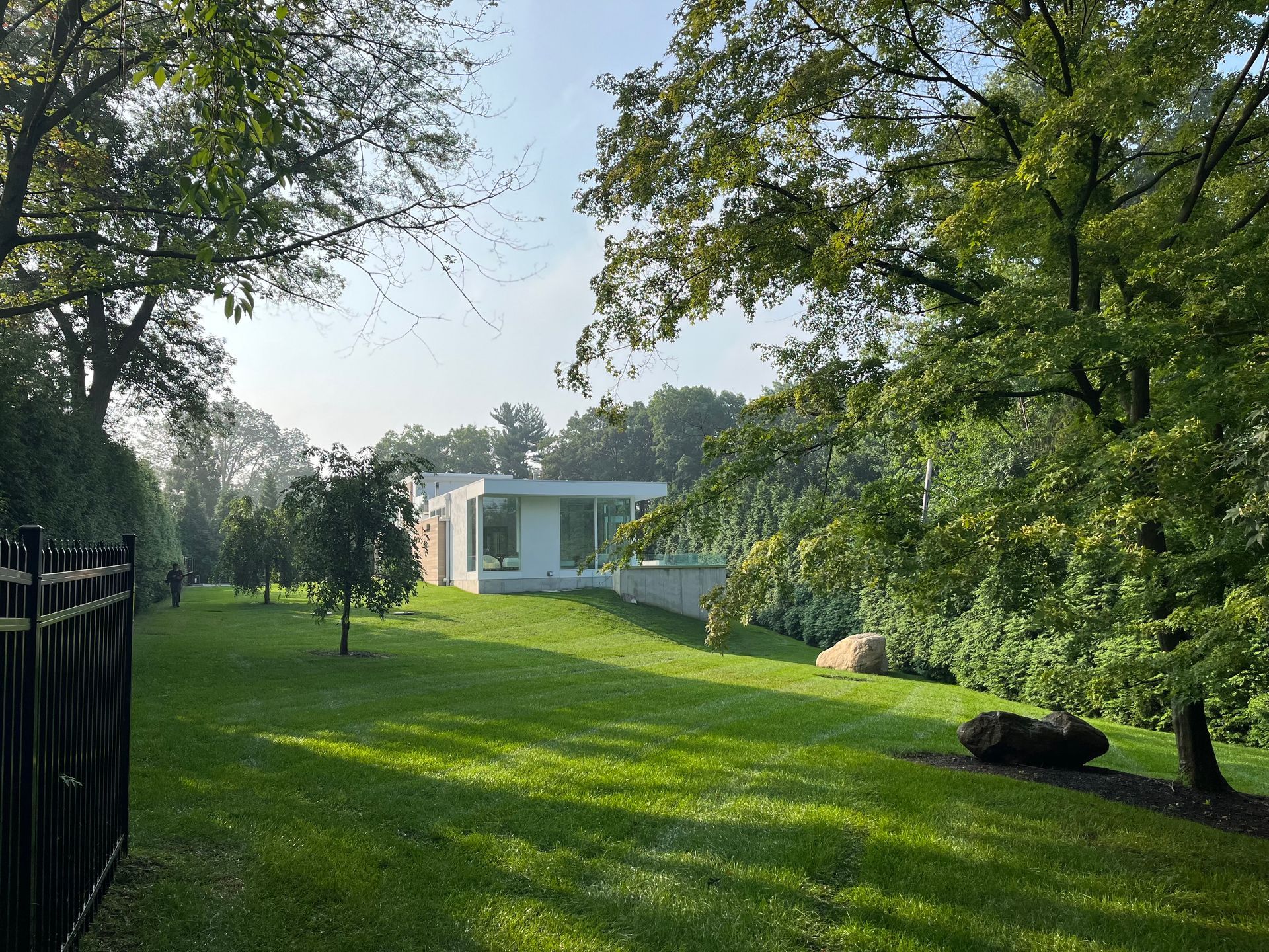 A white house is surrounded by trees and a lush green field.