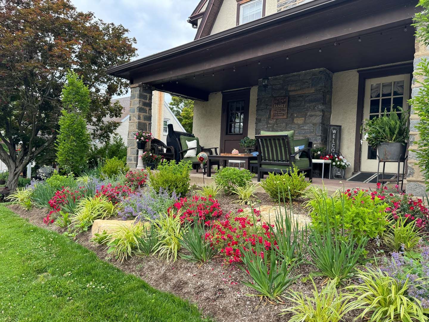 A house with a porch and flowers in front of it.
