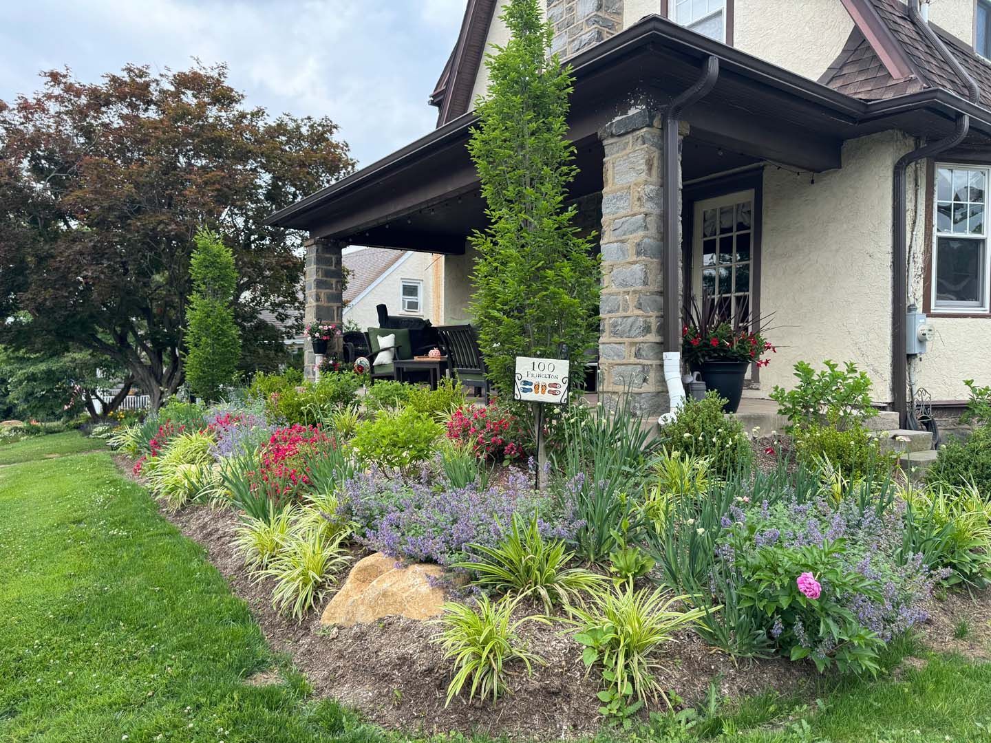 A house with a porch and a garden in front of it.