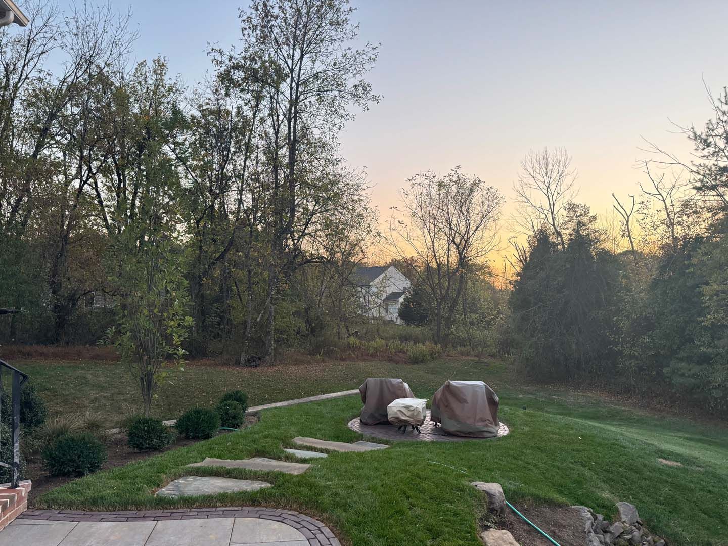 A sunset over a lush green field with a house in the background.