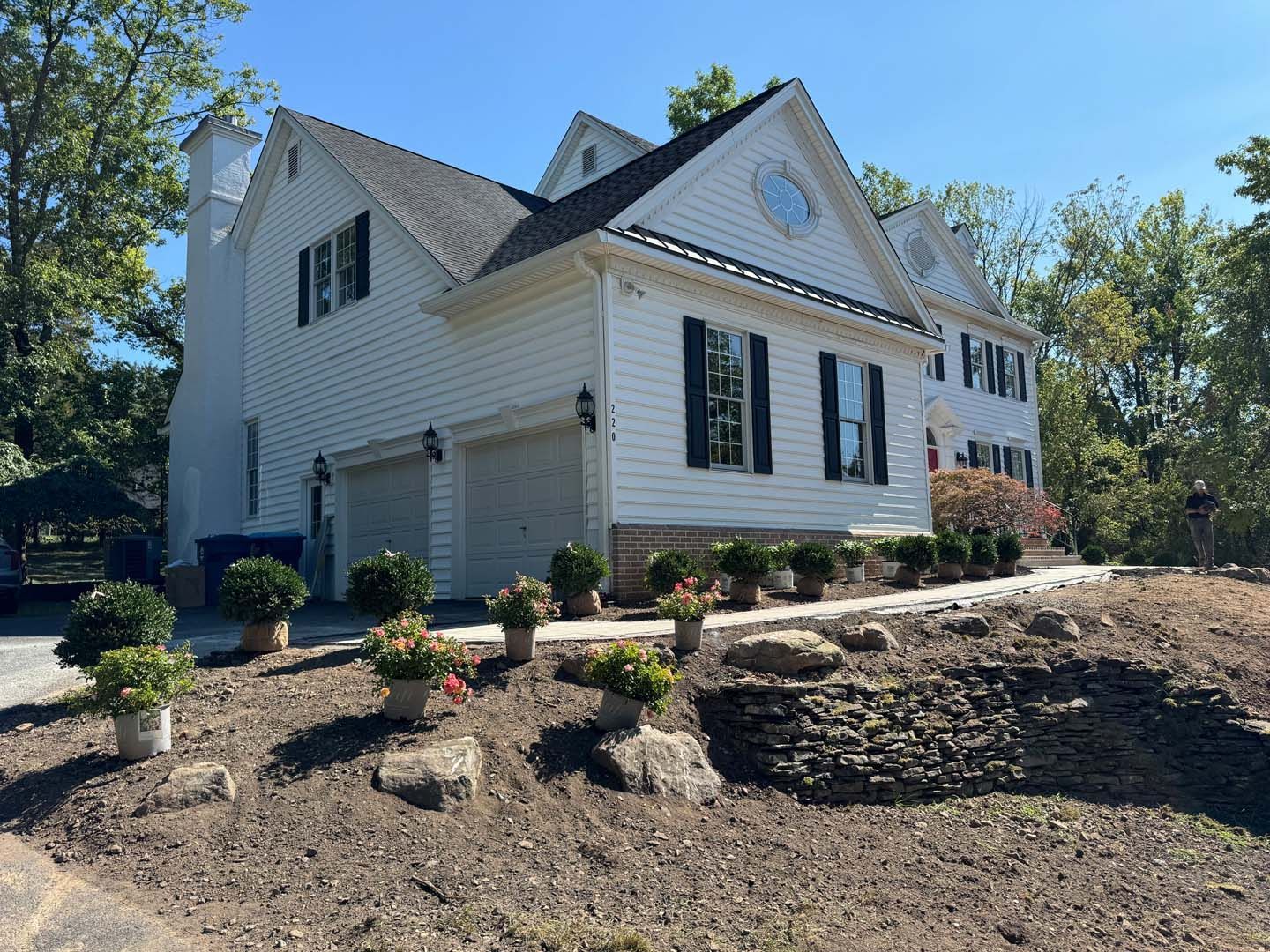 A large white house with black shutters is sitting on top of a hill.