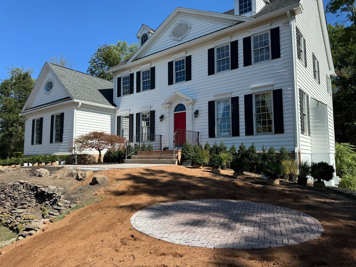 A large white house with black shutters and a red door