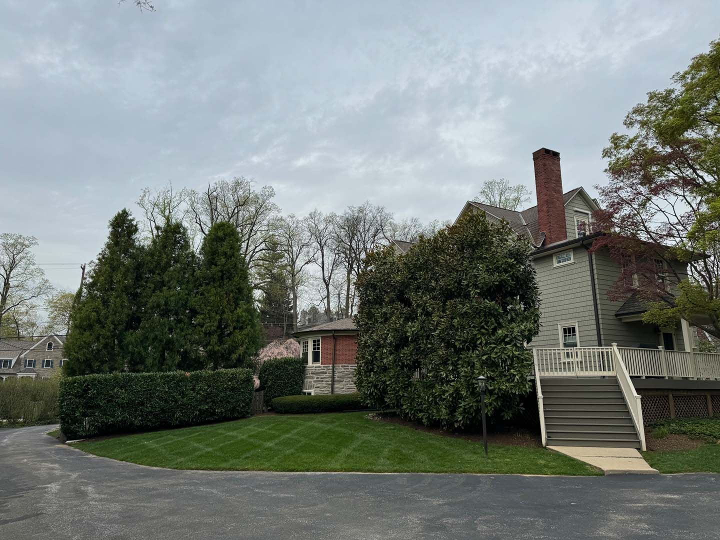 A large house with a lush green lawn and trees in front of it.
