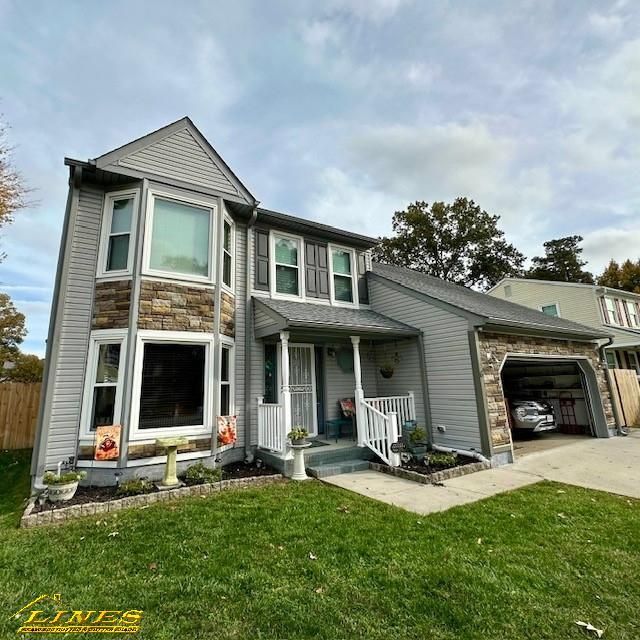 Two-story house with gray siding, stone accents, and attached garage under a cloudy sky.
