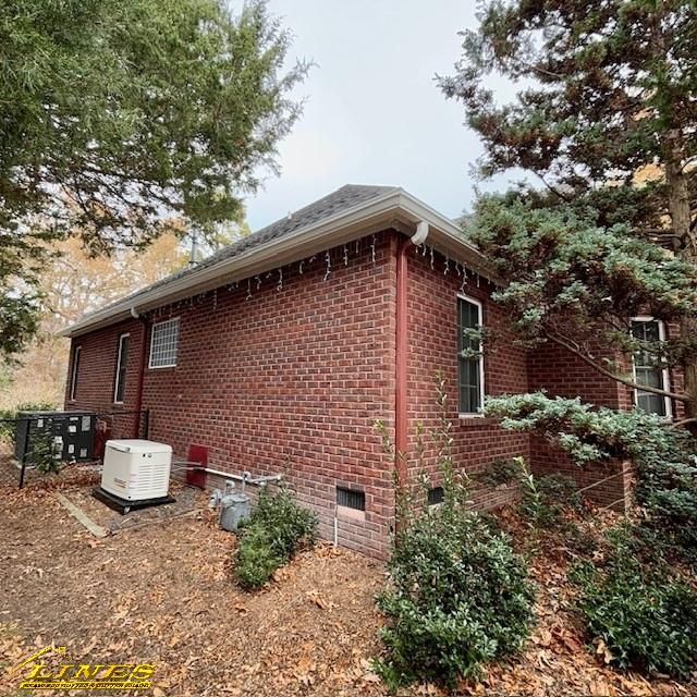Red brick house exterior with trees and generator on the side. Overcast day.